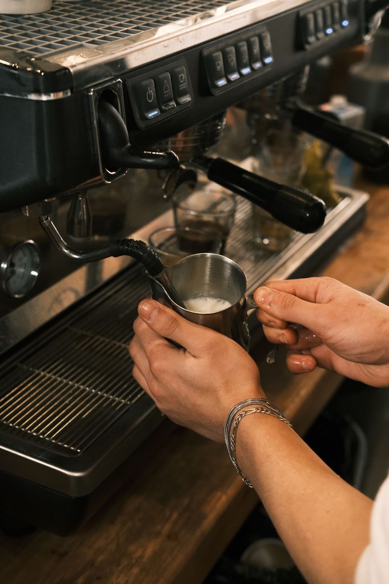 Una barista vaporiza leche en la máquina de espresso de una cafetería