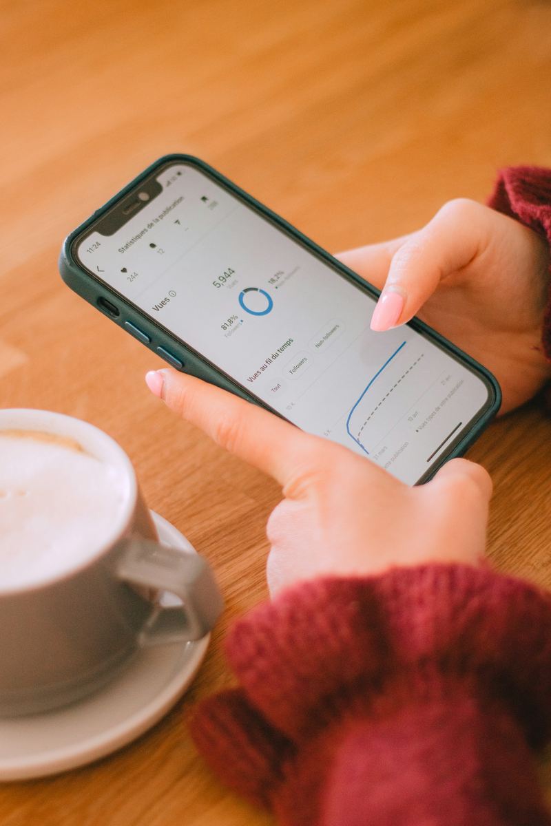 Manos sosteniendo un celular junto a una taza de café